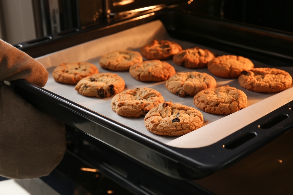 Tray of chocolate chip cookies coming out of the oven